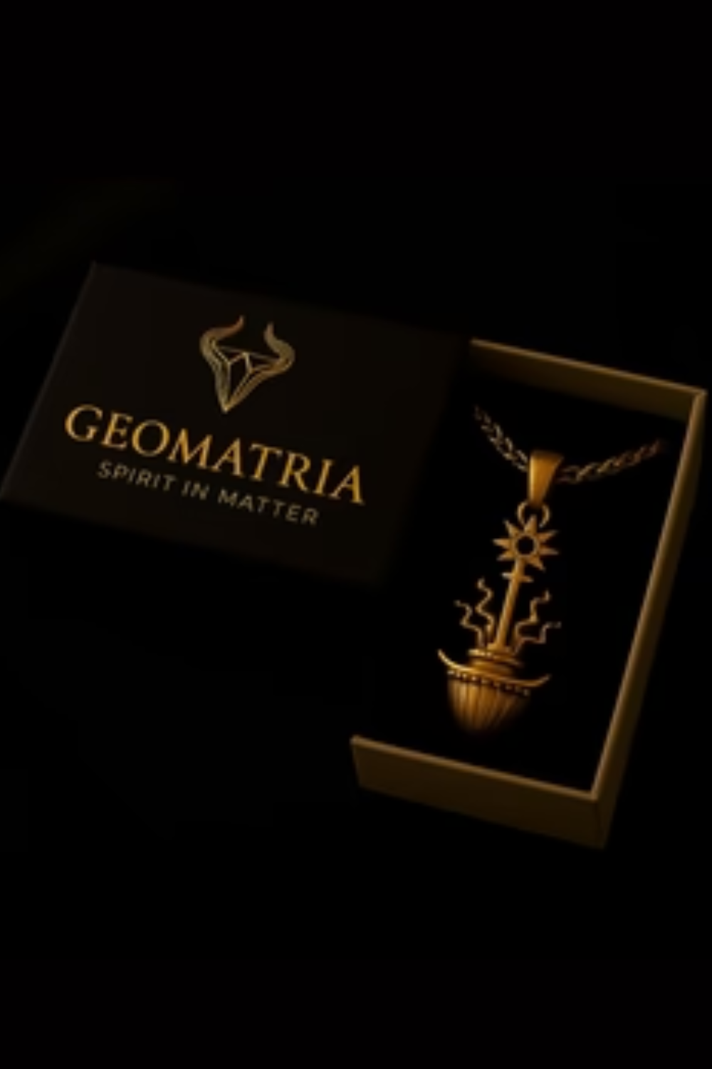 A gold necklace pendant with a geometric design is displayed in a black box with the text "Geomatria SPIRIT IN MATER" printed on it.