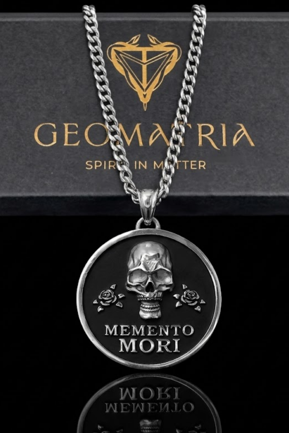 a silver-toned pendant necklace with a circular medallion featuring a skull and roses, and the text "Memento mori" below the medallion.