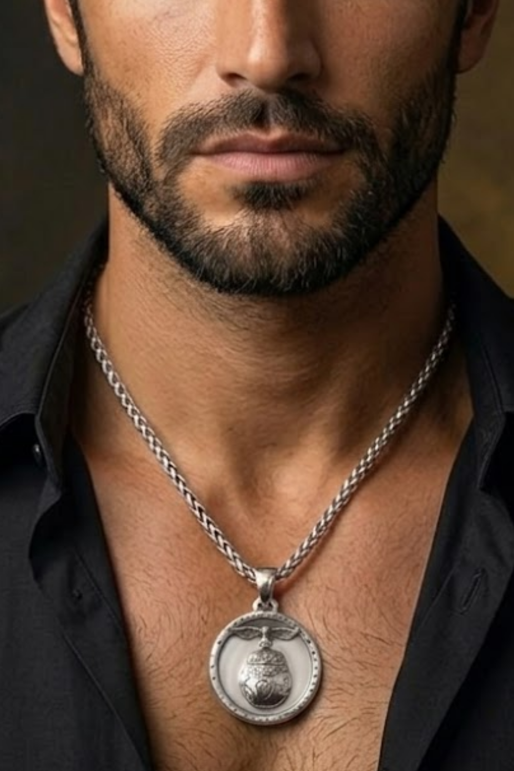 A close-up of a man's neck and chest area, with a silver necklace and a pendant visible.