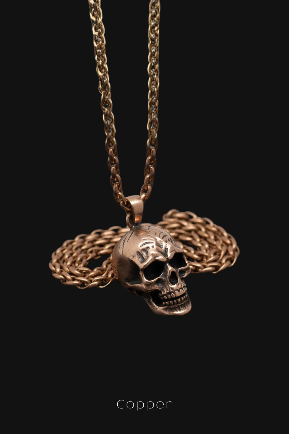 A gold-colored necklace with a pendant in the shape of a skull, suspended against a black background.