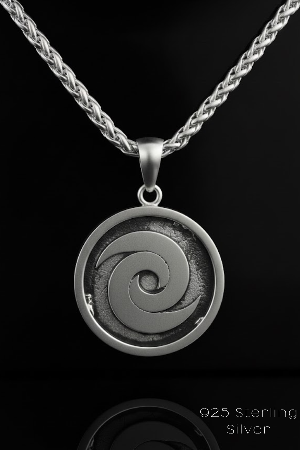 A silver pendant necklace with a circular pendant featuring a spiral design.