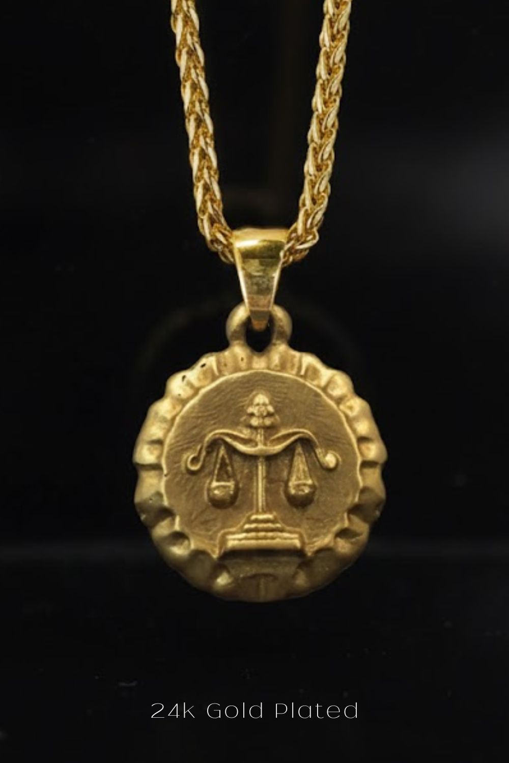 A 24k gold-plated pendant featuring a medallion-shaped design with a scale and a symbol, suspended from a chain.
