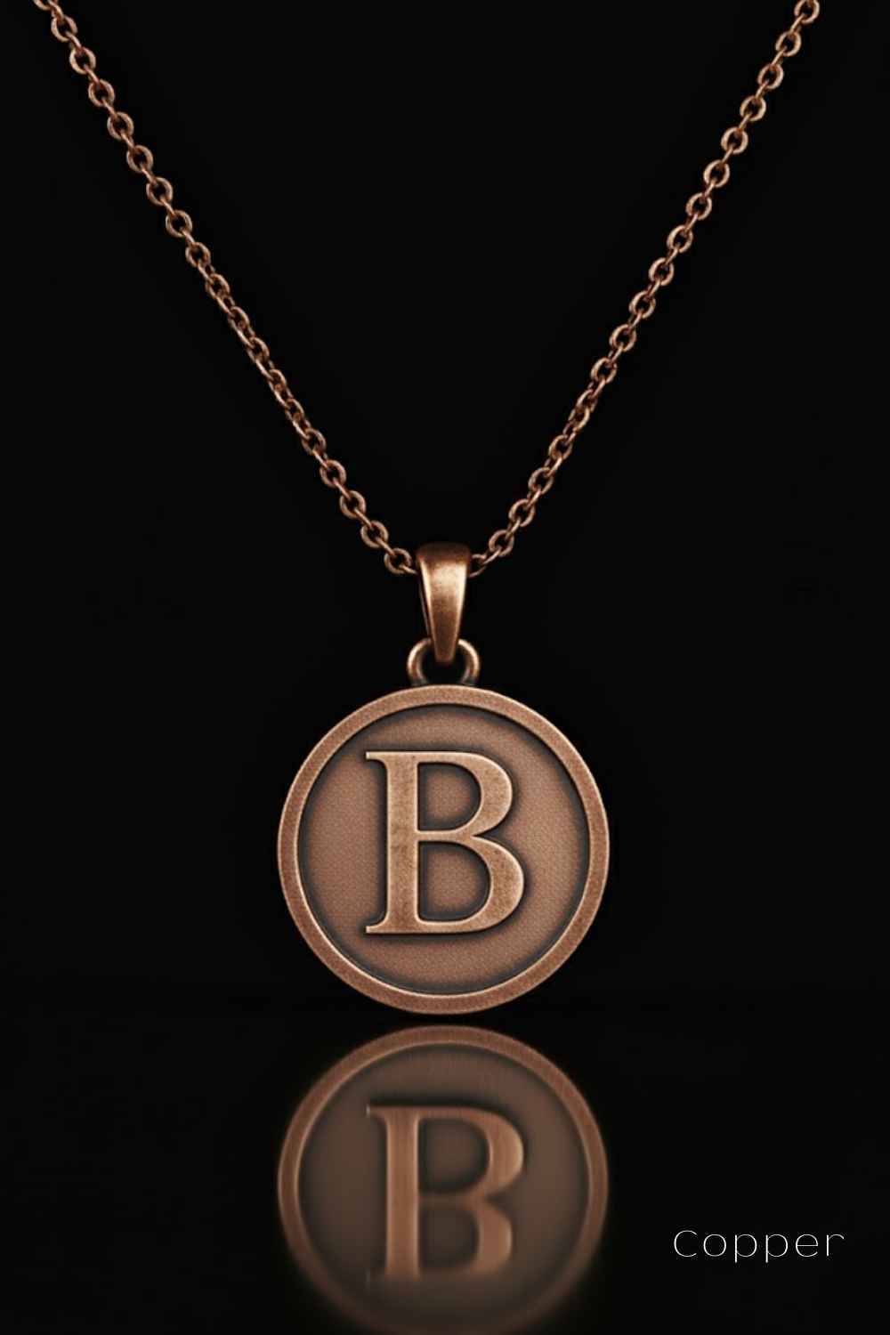 A copper-colored pendant necklace with a large circular pendant featuring the letter "B" in the center.