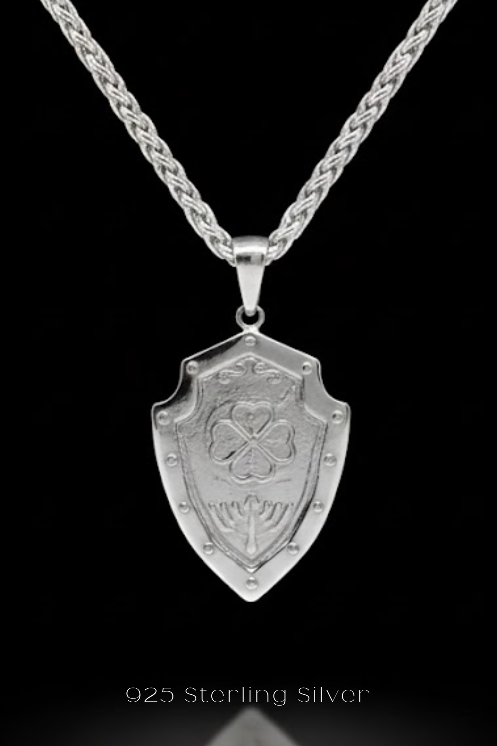 A silver-colored pendant necklace with a shield-shaped pendant featuring a four-leaf clover design.