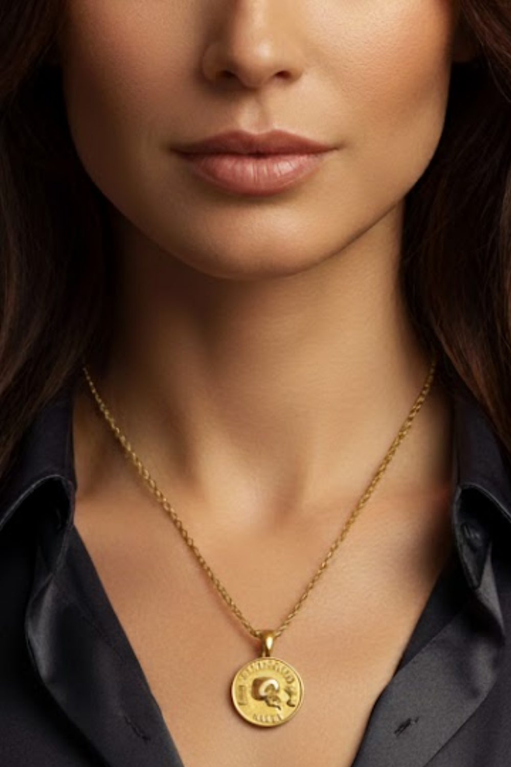 A close-up of a woman's neck and chest area, with a gold necklace featuring a pendant.