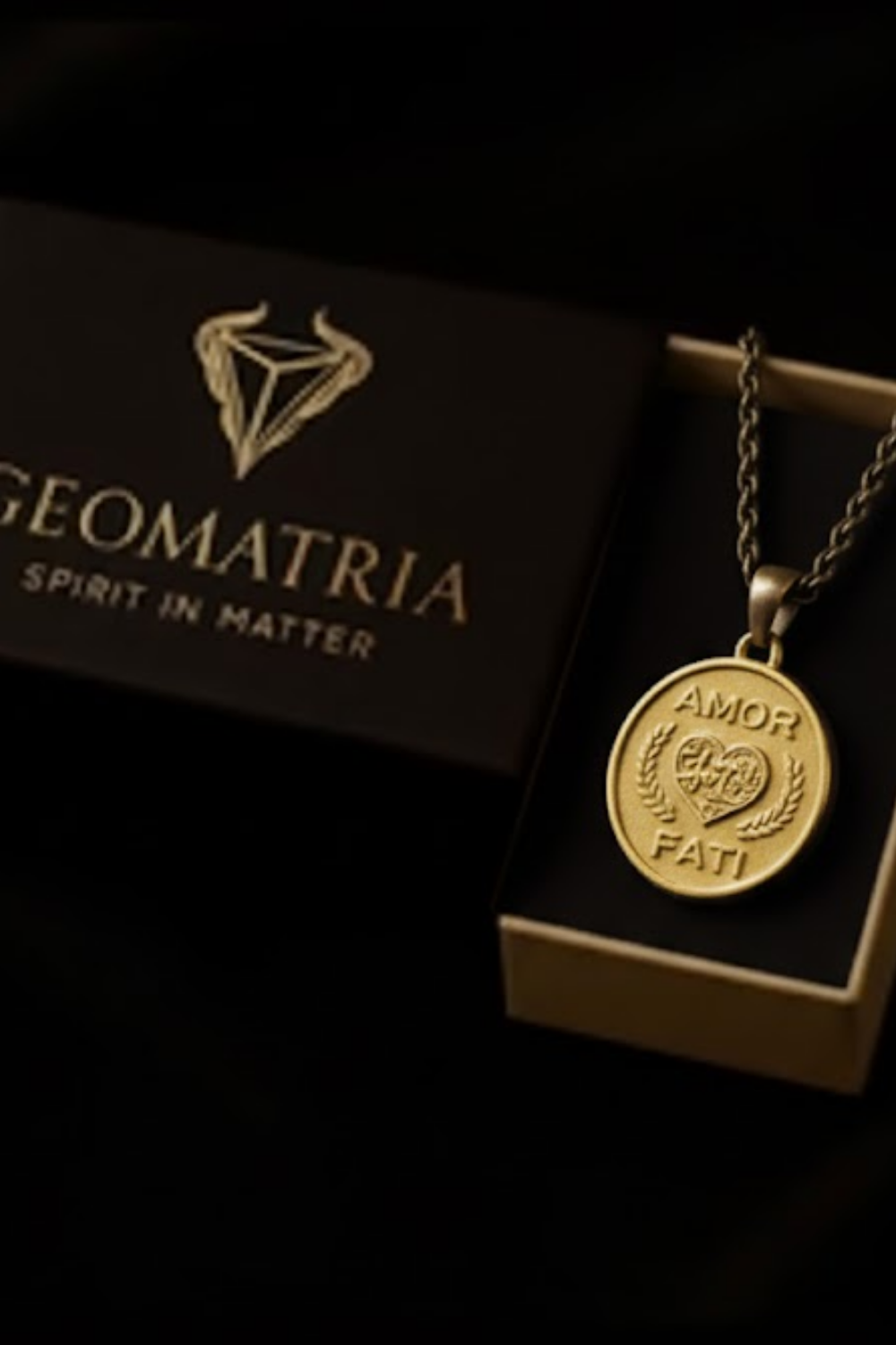 a gold-colored pendant with the inscription "AMOR FATT" and a black box with the text "GEOMATRIA SPIRIT IN MATTERS" on it.