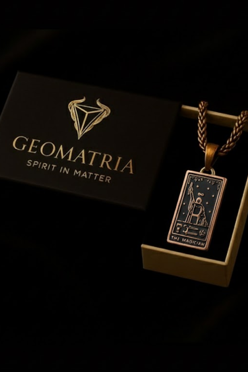 a pendant with a geometric design and a tarot card pendant, both displayed in a black box with gold lettering.