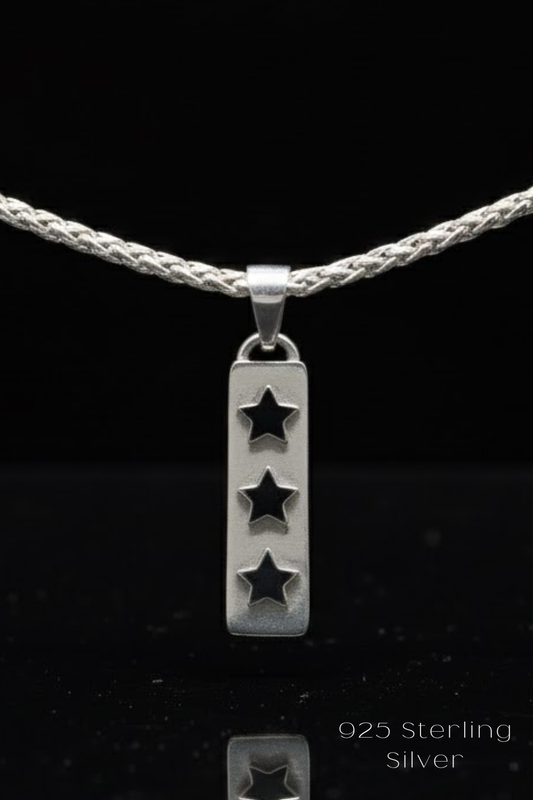 A silver pendant with three stars is suspended from a silver chain against a black background.