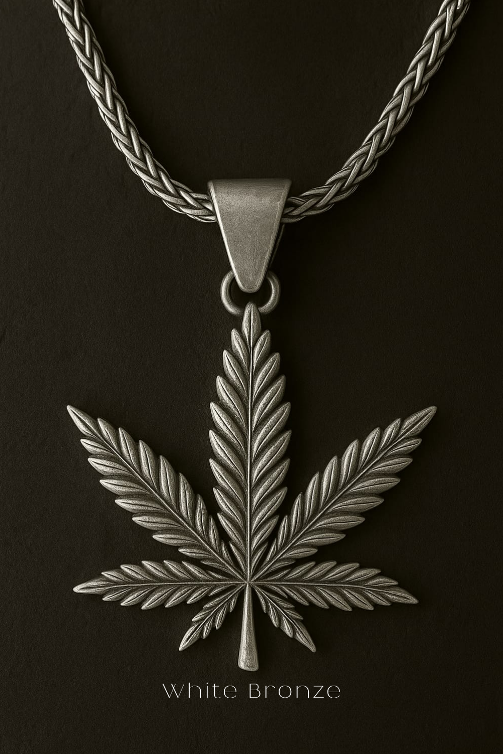 A white bronze pendant featuring a detailed leaf design is displayed against a dark background.