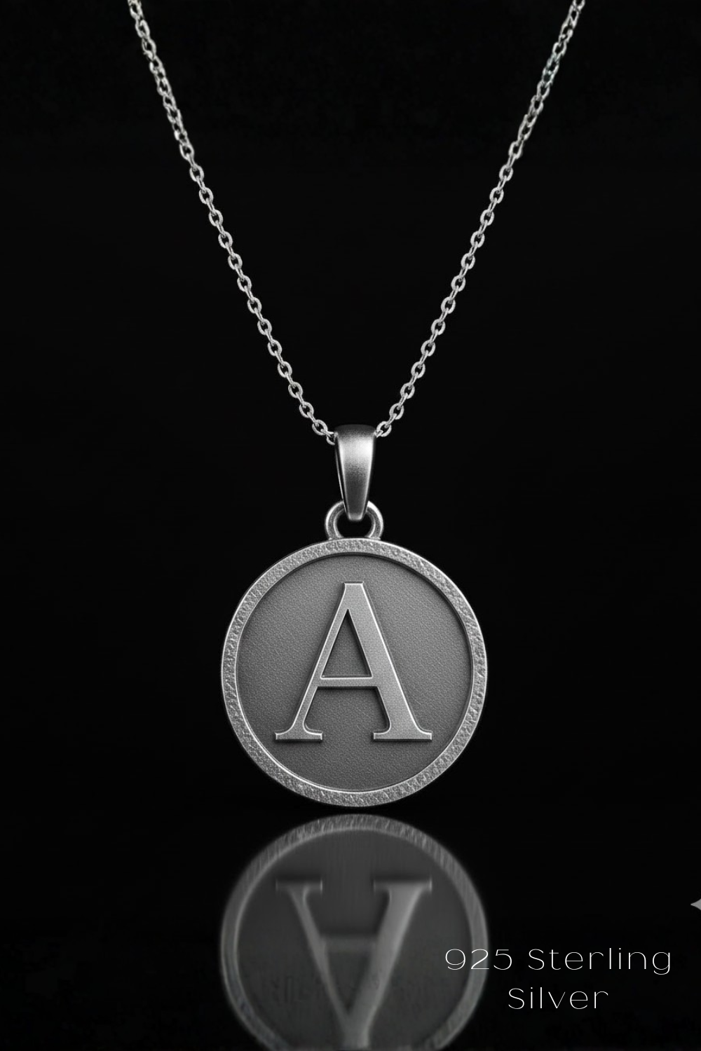 A silver-colored pendant necklace with a large letter "A" in the center, suspended from a chain against a black background.