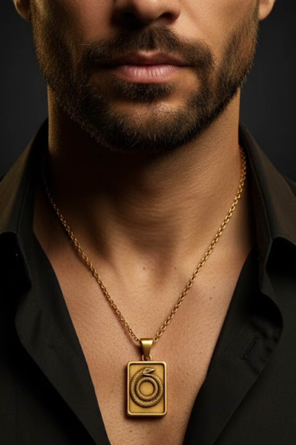A close-up of a man's neck and chest area, with a gold necklace featuring a pendant with a snake design.