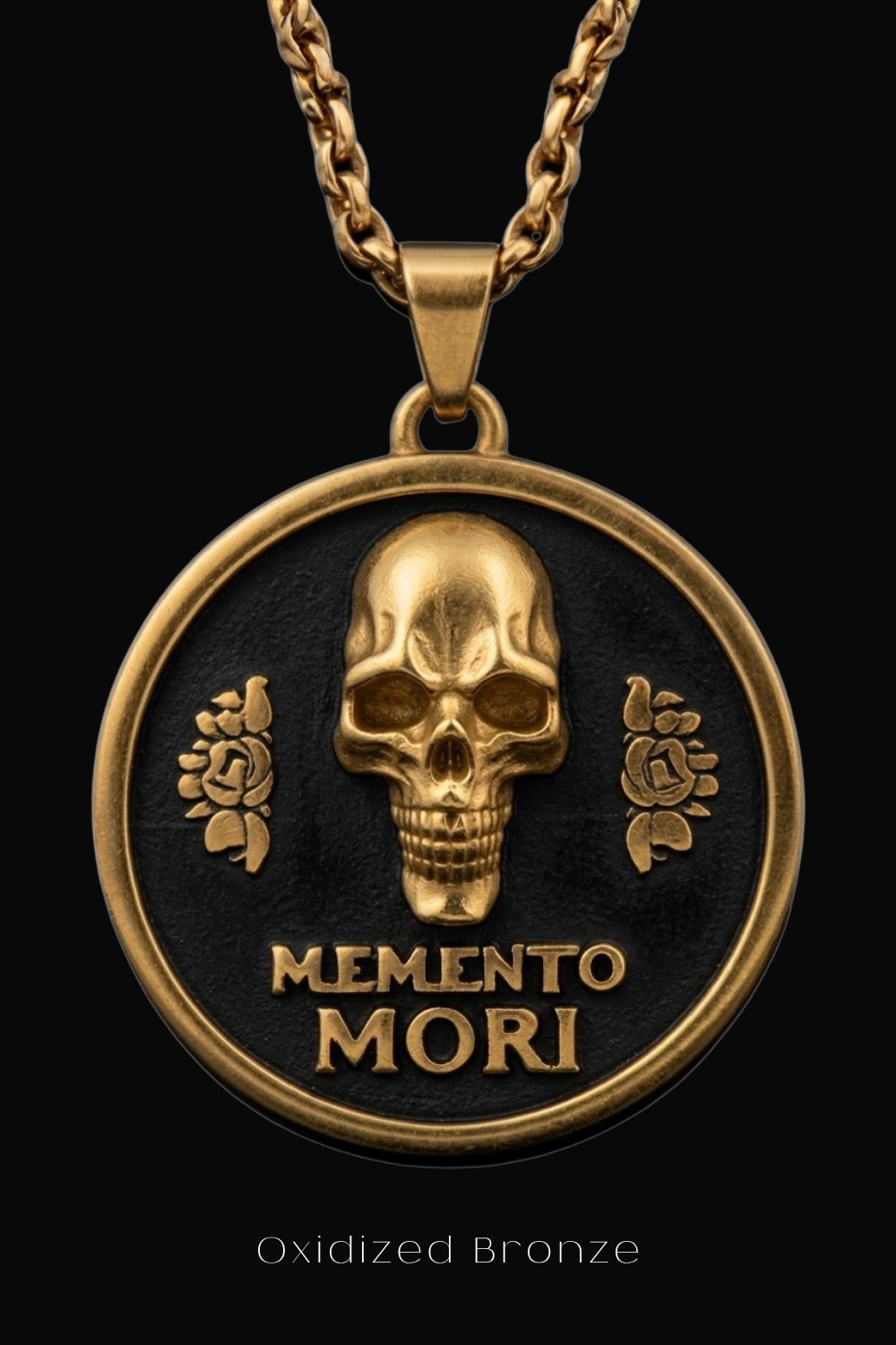 a gold-colored pendant with a black background and a gold-colored skull design. The pendant has the text "MEMENTO MORI" engraved on it.