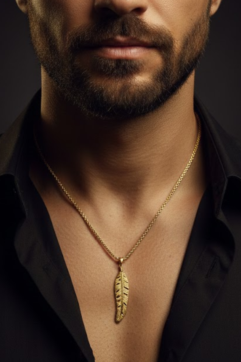 A close-up of a man's neck and chest area, with a gold-colored necklace featuring a feather pendant.