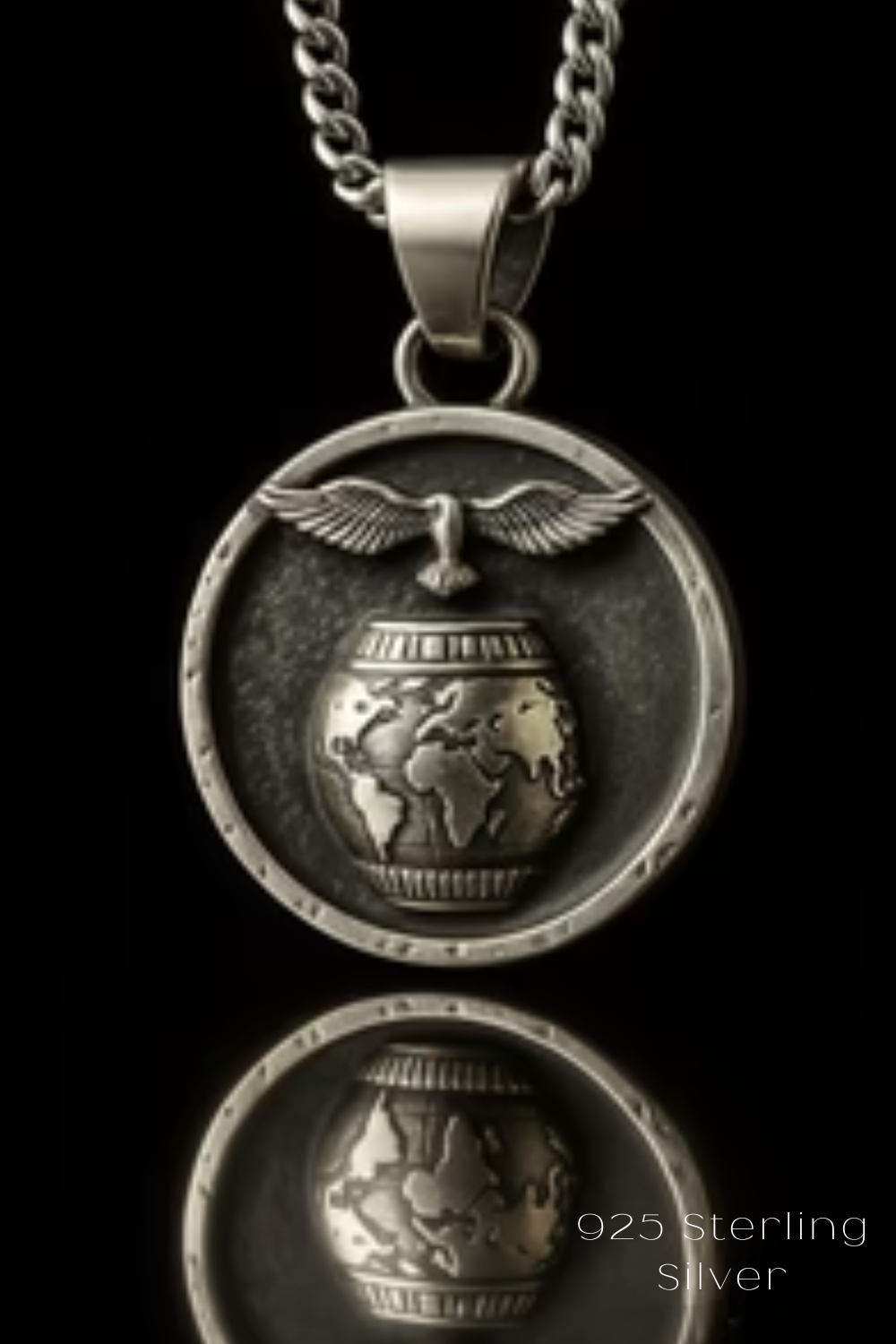 A silver pendant necklace with a circular design featuring a globe and a bird in flight.