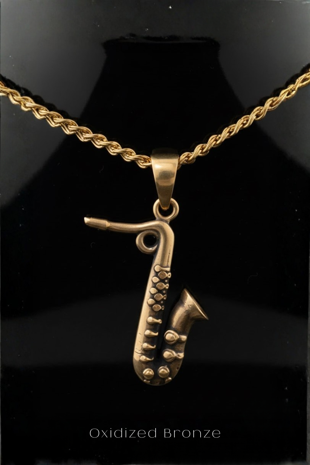 A gold-colored pendant in the shape of a saxophone is displayed against a black background.