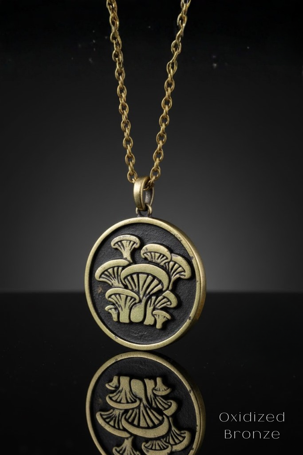 A pendant necklace with a circular design featuring a mushroom-like pattern in gold and black tones.