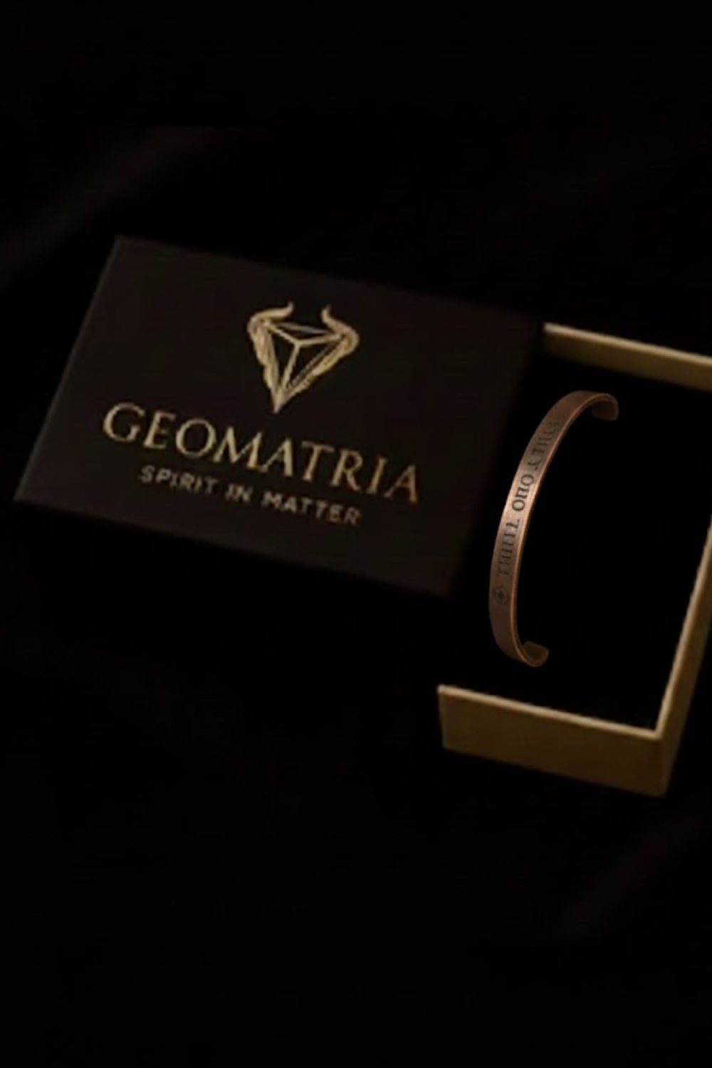 a black box with a gold logo and the text "GEOMATRIIA SPIRIT IN MATER" on it, along with a bracelet inside the box.