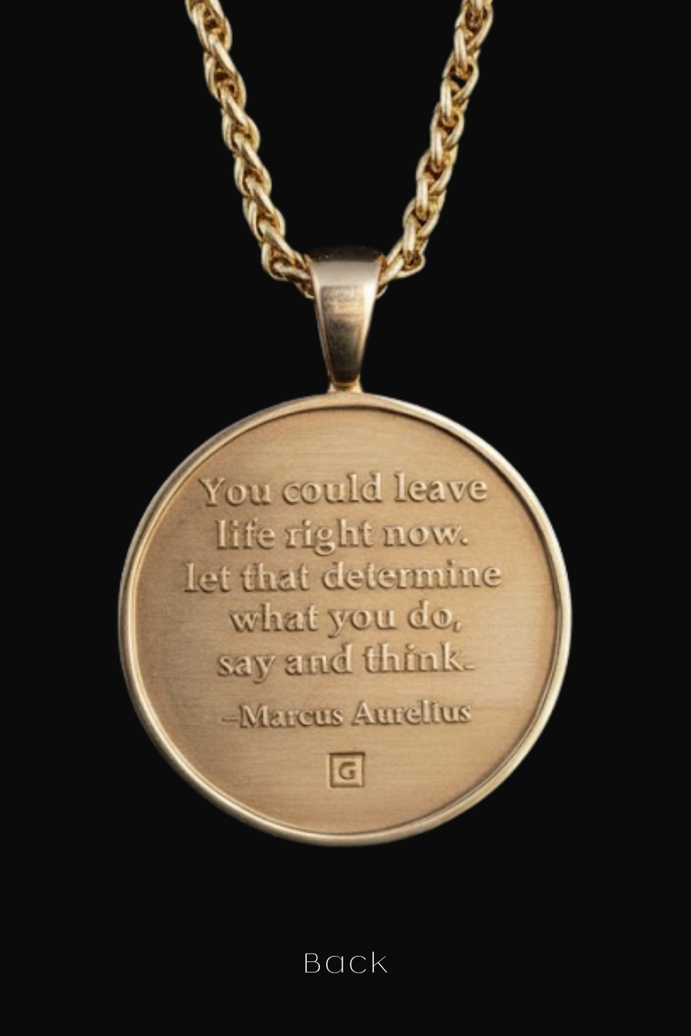 A gold-colored pendant necklace with a circular medallion featuring a quote by Marcus Aurelius.