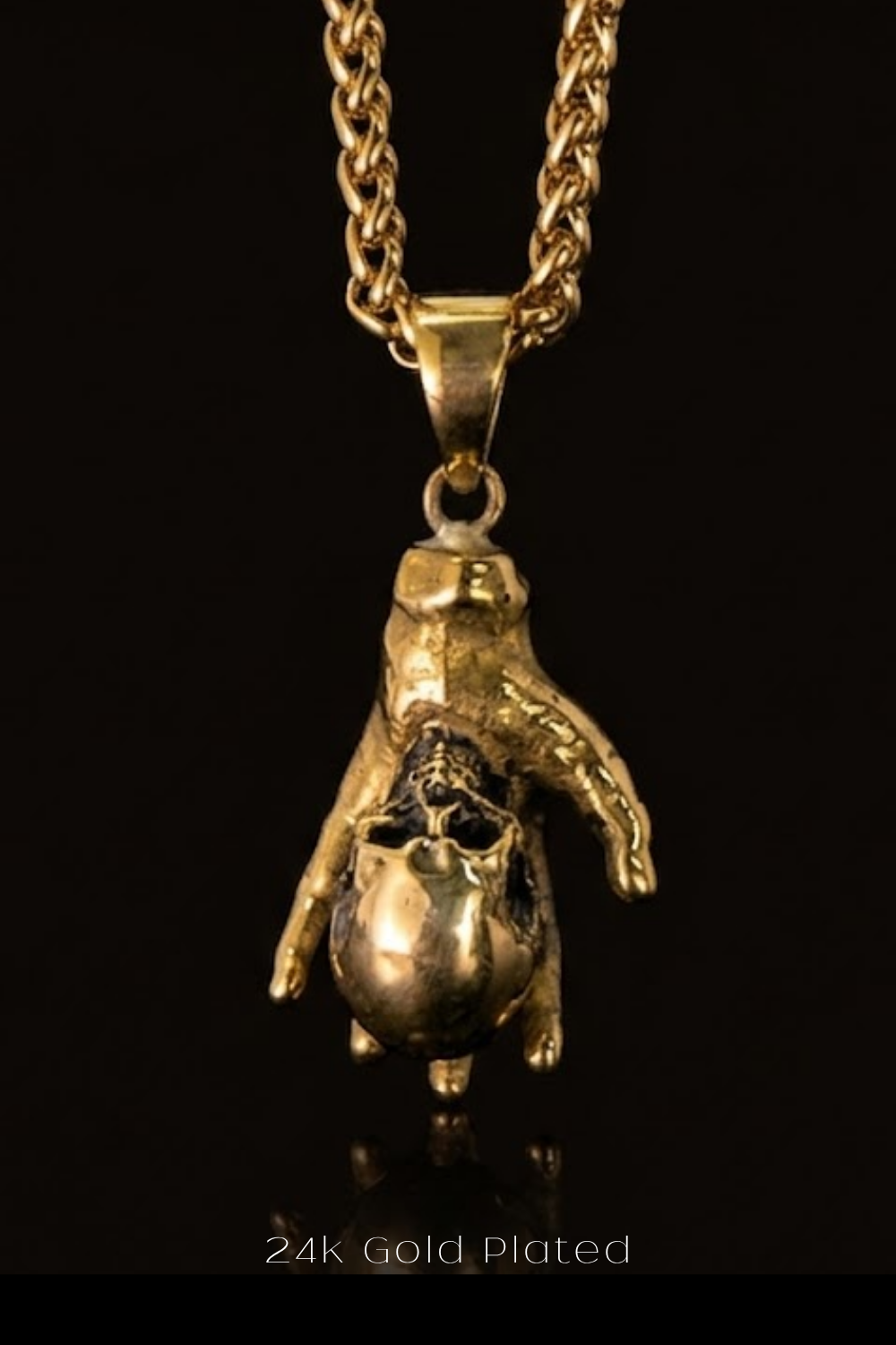 A gold-plated pendant necklace with a unique design featuring a hand-like figure.