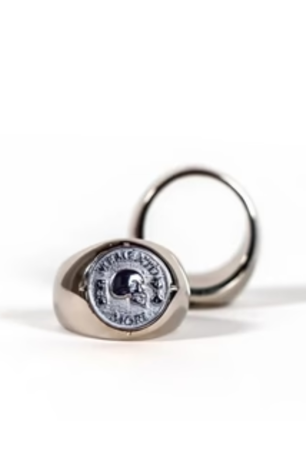 a silver ring with a round medallion on it, which has a skull and crossbones design.