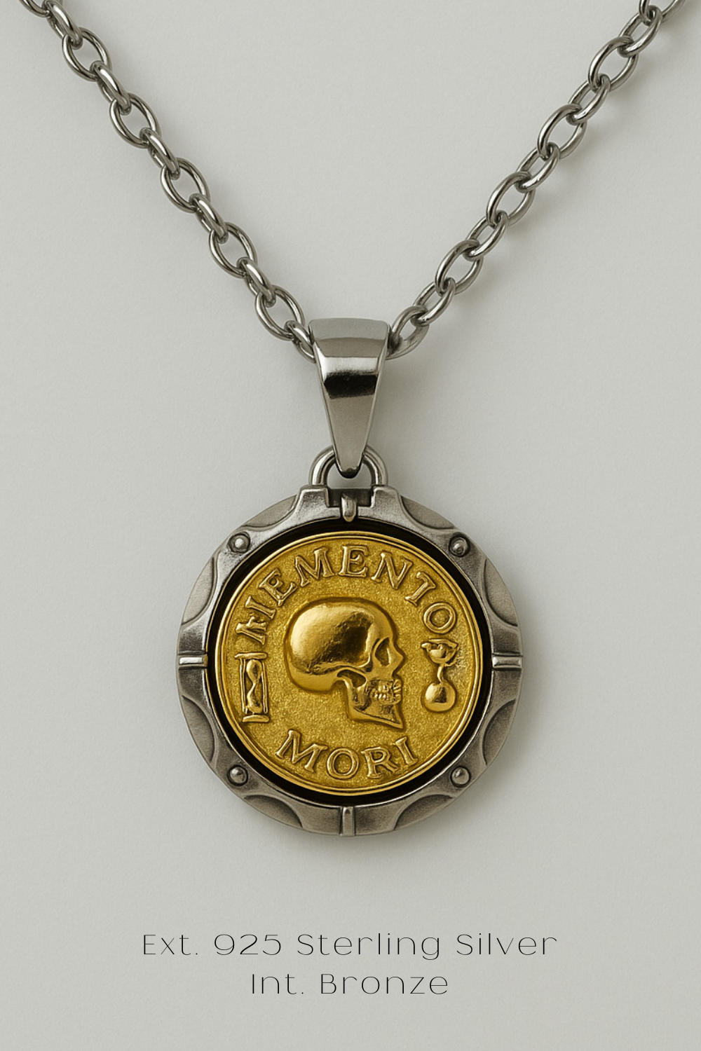A necklace with a pendant featuring a gold-colored skull and the text "MORI" engraved on it. The pendant is made of sterling silver and has a chain attached to it.