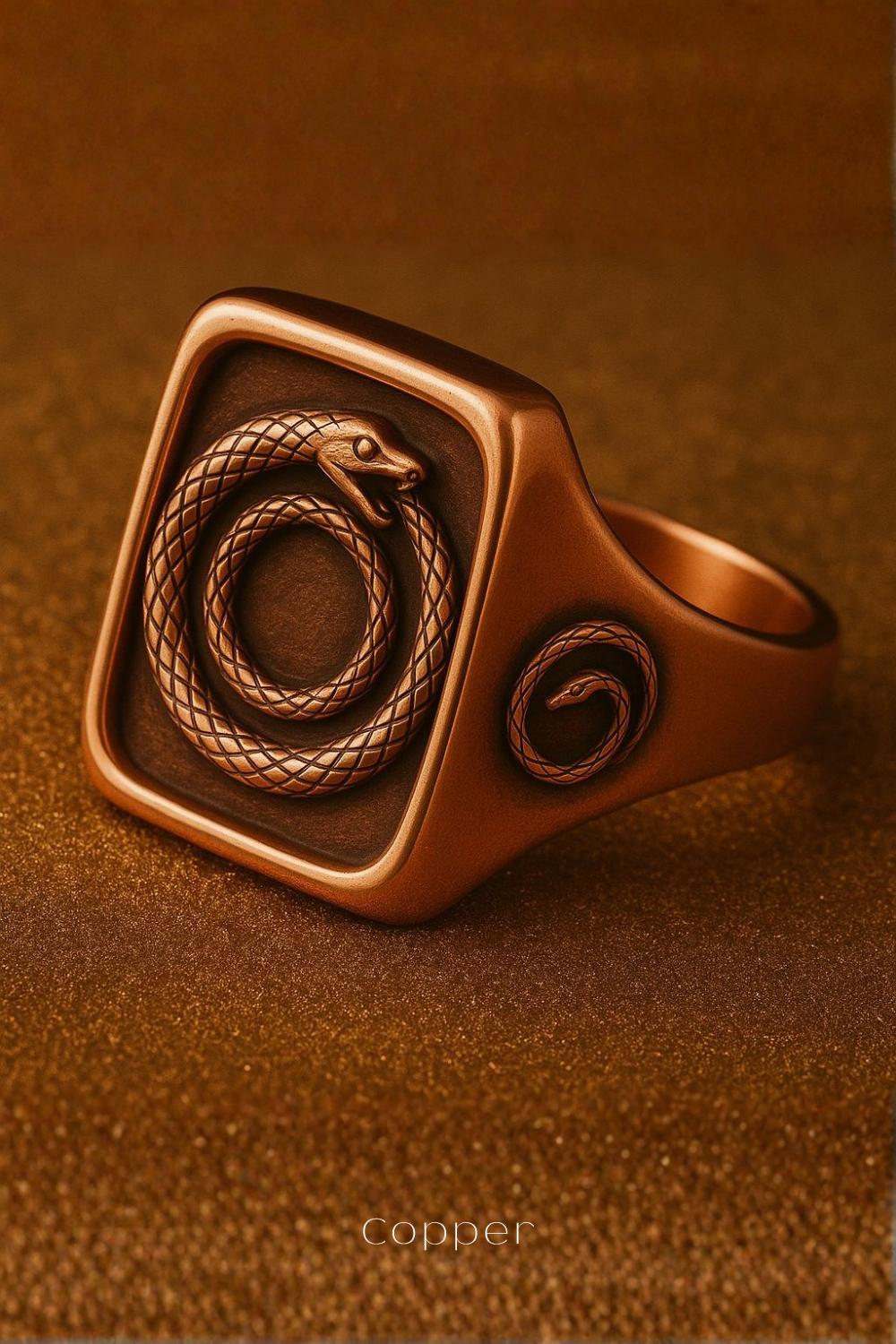 A copper-colored ring with a square-shaped design featuring a snake and a spiral pattern.