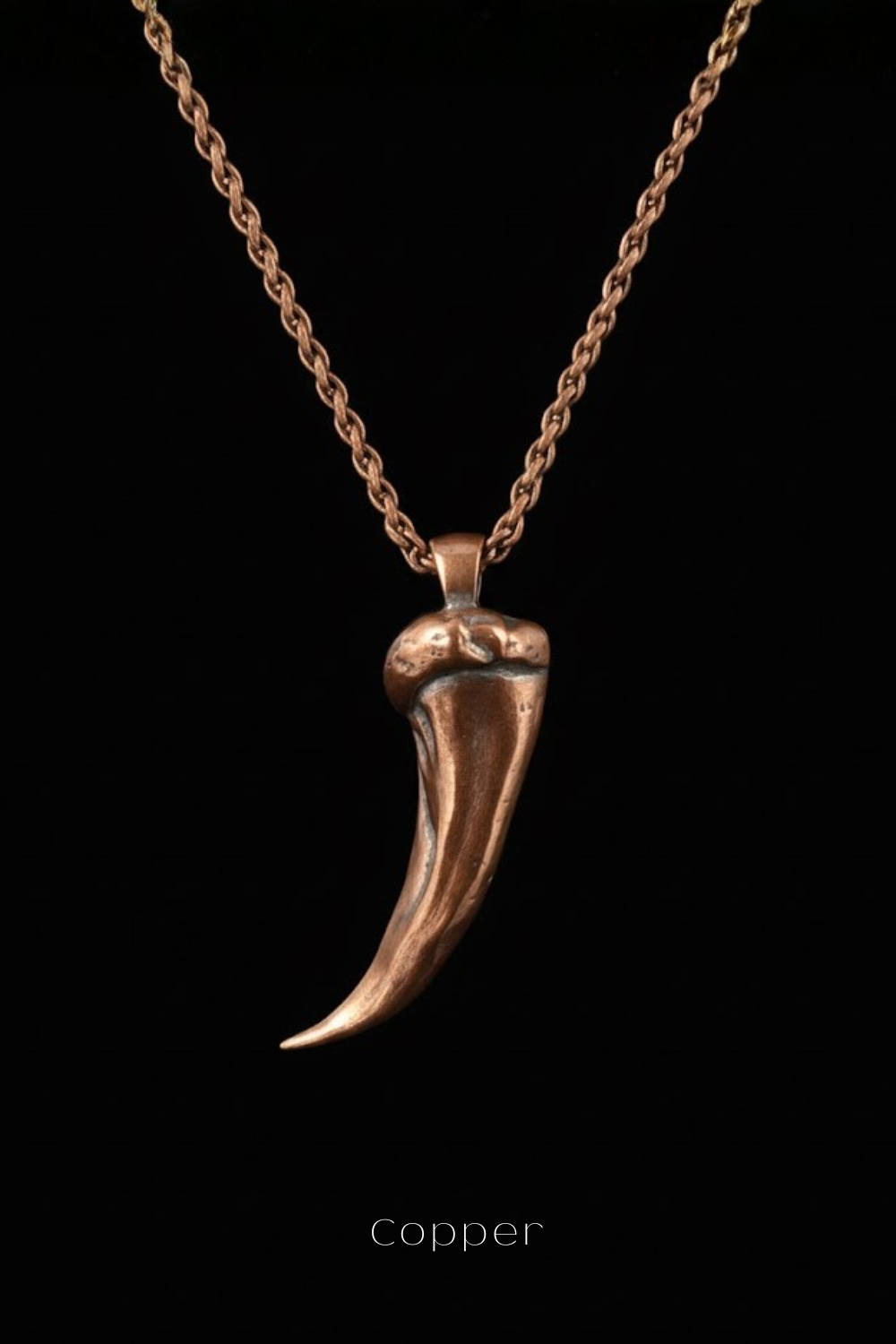 A copper-colored pendant necklace with a single, elongated pendant against a black background.
