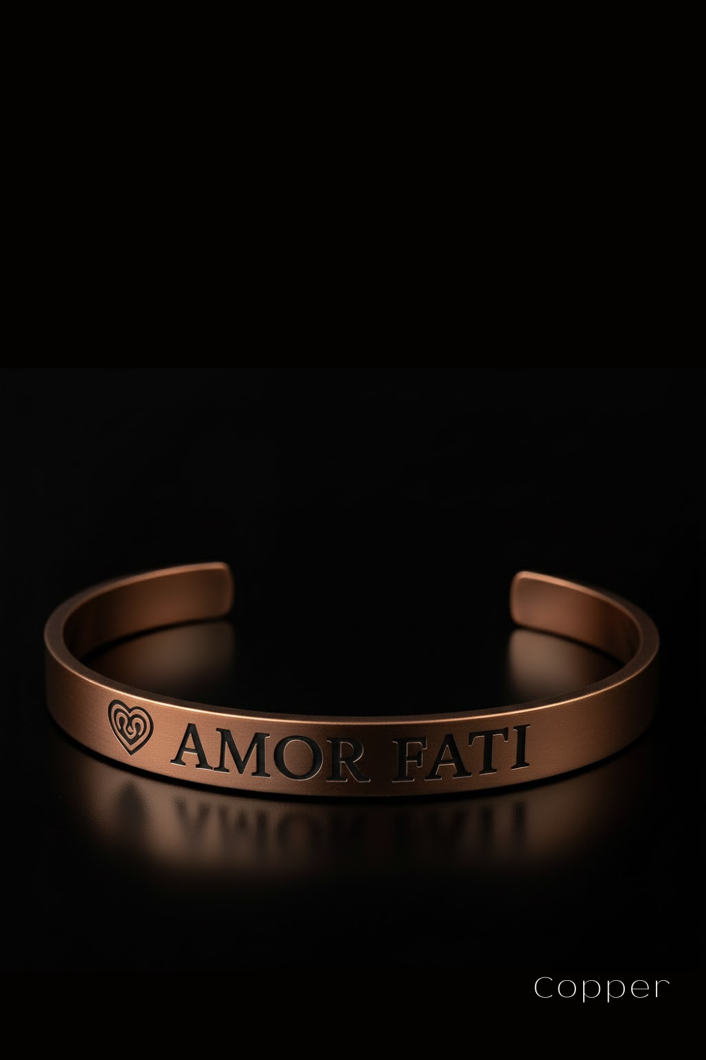 A copper bracelet with the engraved text "Amor Fati" on it, set against a black background.