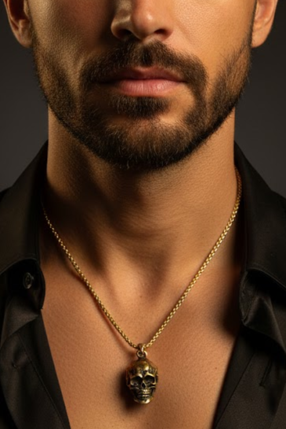 A close-up of a man's neck and chest area, with a gold-colored necklace featuring a skull pendant.