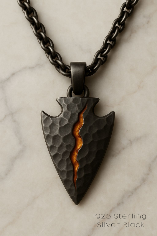 A black pendant with a carved design and a small orange stripe running through it, suspended from a chain.