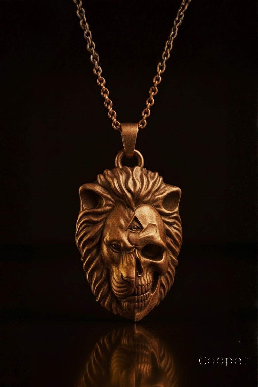 A gold-colored pendant necklace with a lion's head design, featuring a skull-like face and a split lion's head, against a dark background.