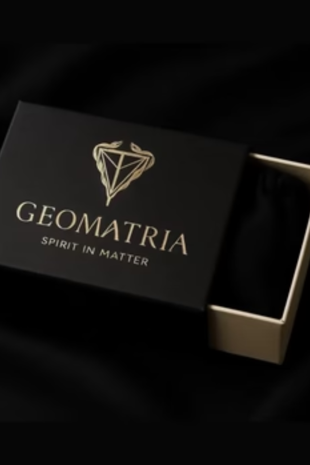 A black box with a gold logo and text, partially open to reveal a black object inside.