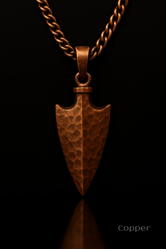 A copper-colored arrowhead pendant is displayed against a black background, with the word "Copper" written in the bottom right corner.