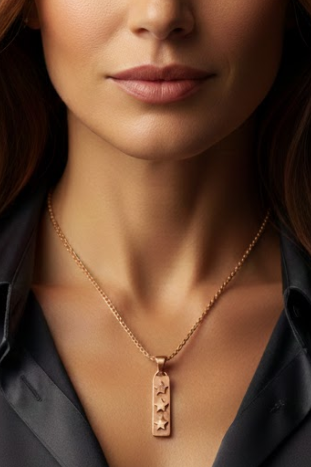 A close-up of a woman's neck and chest area, with a gold necklace featuring a pendant with three stars.