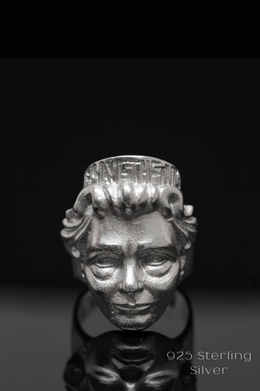 A silver ring featuring a detailed, sculpted face design.
