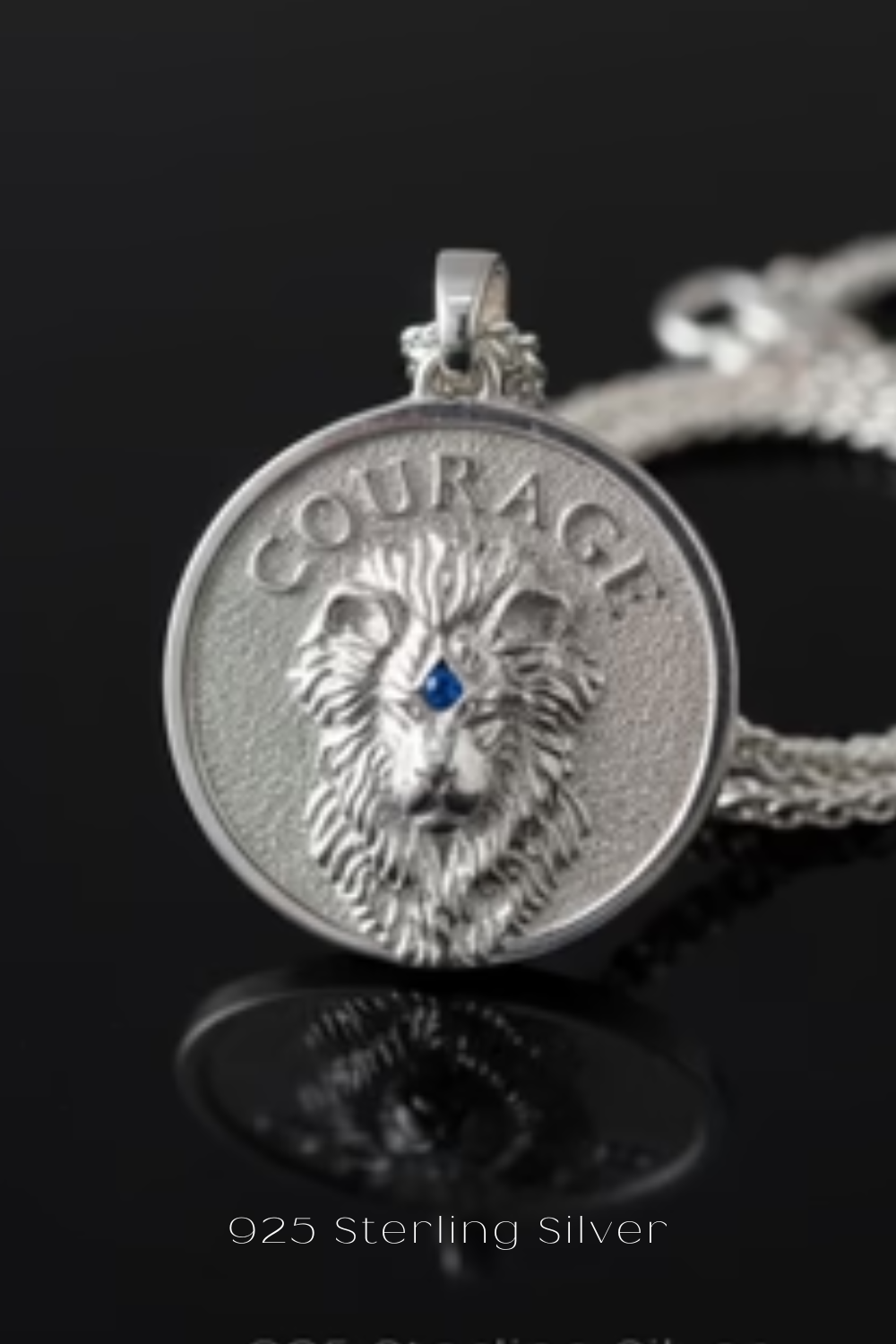 A silver pendant with a lion's head design, featuring the word "COURAGE" engraved on it.