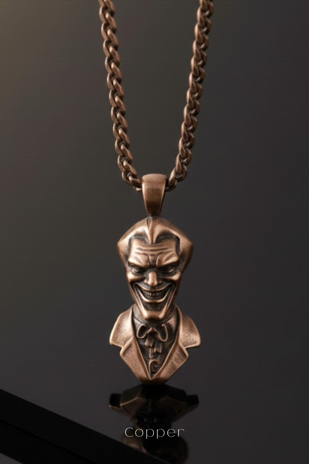 A bronze-colored pendant in the shape of a smiling man's head wearing a suit and tie.