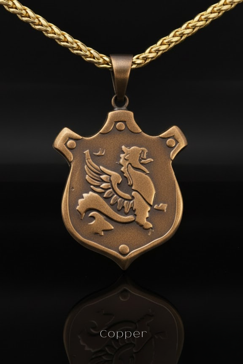 A gold-colored pendant with a shield-shaped design featuring a winged creature, possibly a dragon or a mythical creature, and the word "Copper" written below it.