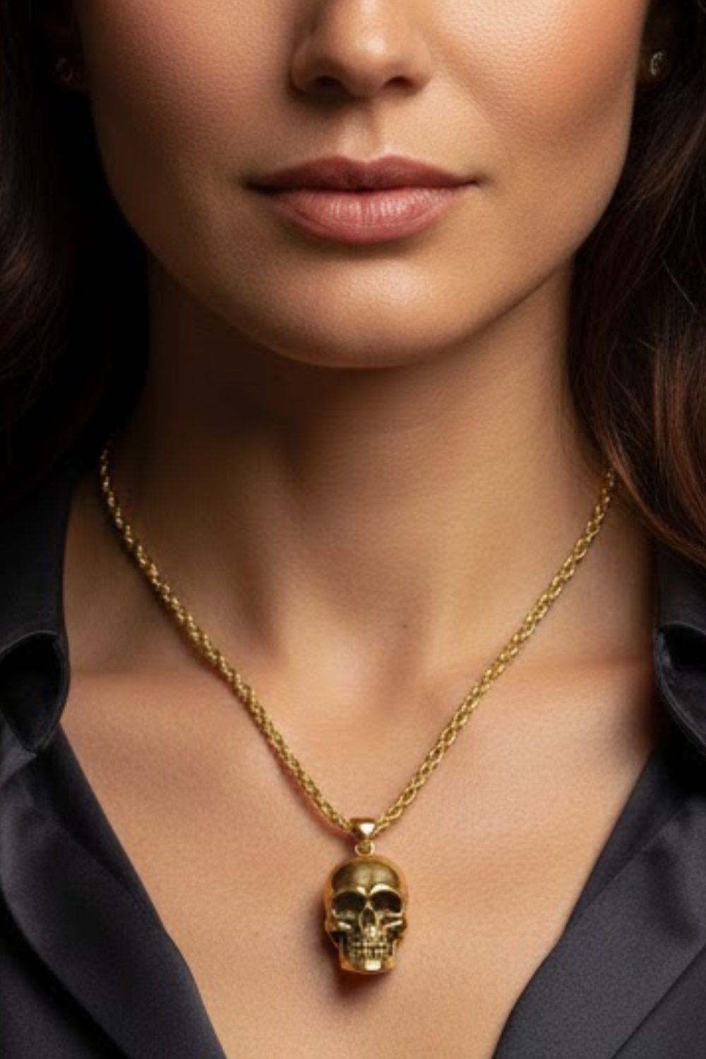 A close-up of a woman's neck and chest area, with a gold-colored necklace featuring a pendant in the shape of a skull.
