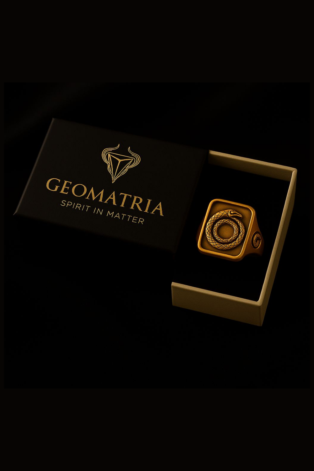 A black box with a gold geometric design and the text "Geomatria" on it, along with a gold ring with a snake motif inside the box.