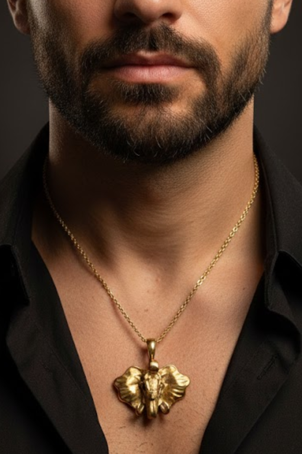 A close-up of a man's neck and chest area, with a gold-colored pendant necklace featuring an elephant design.