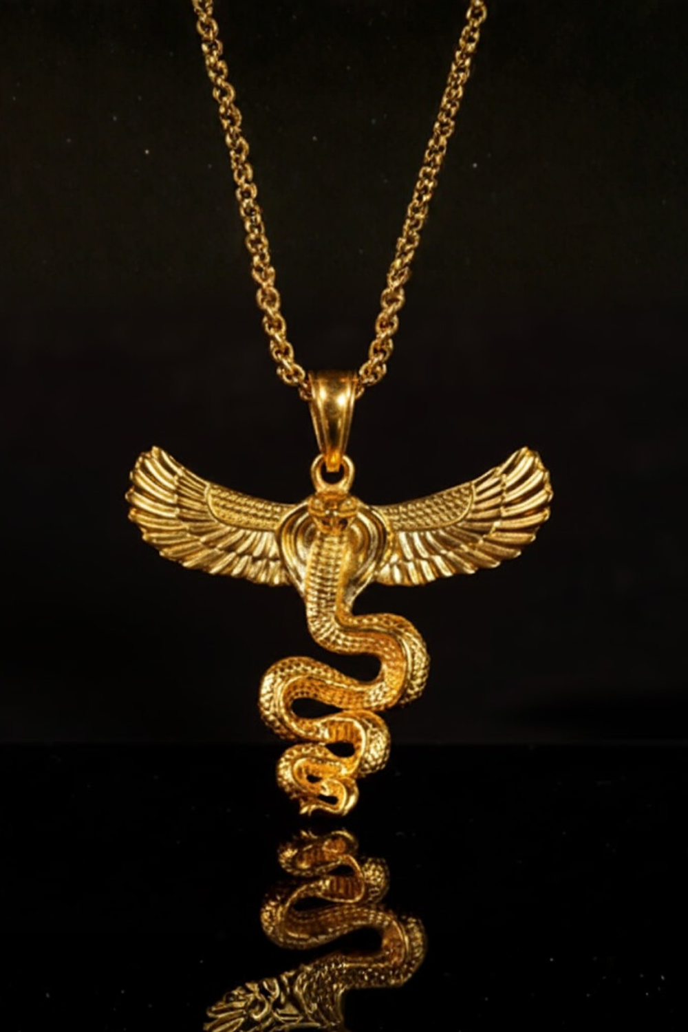 A gold-colored pendant necklace with a snake design and wings, suspended against a black background.