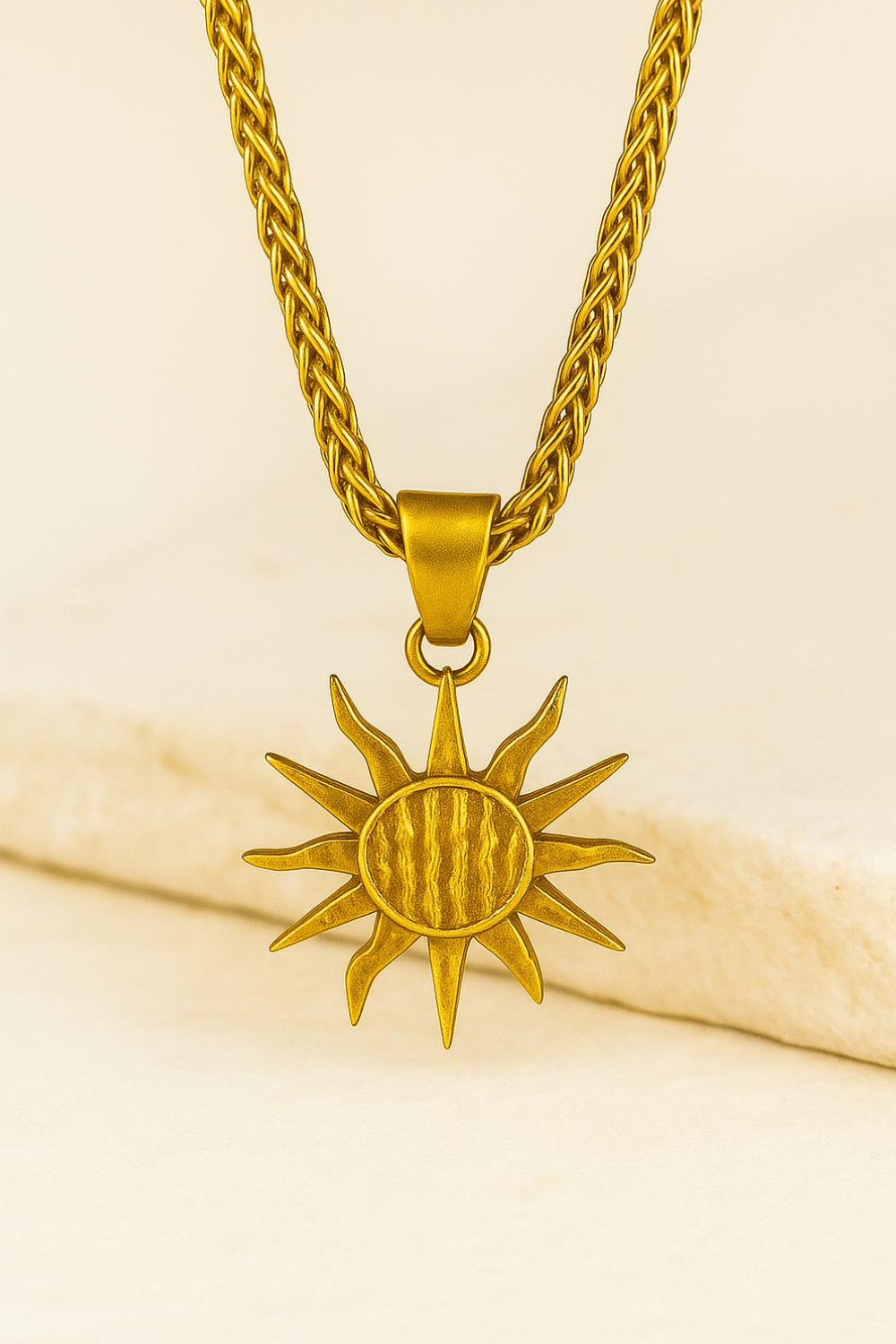 A gold-colored pendant necklace with a sun-shaped pendant is displayed against a white background.