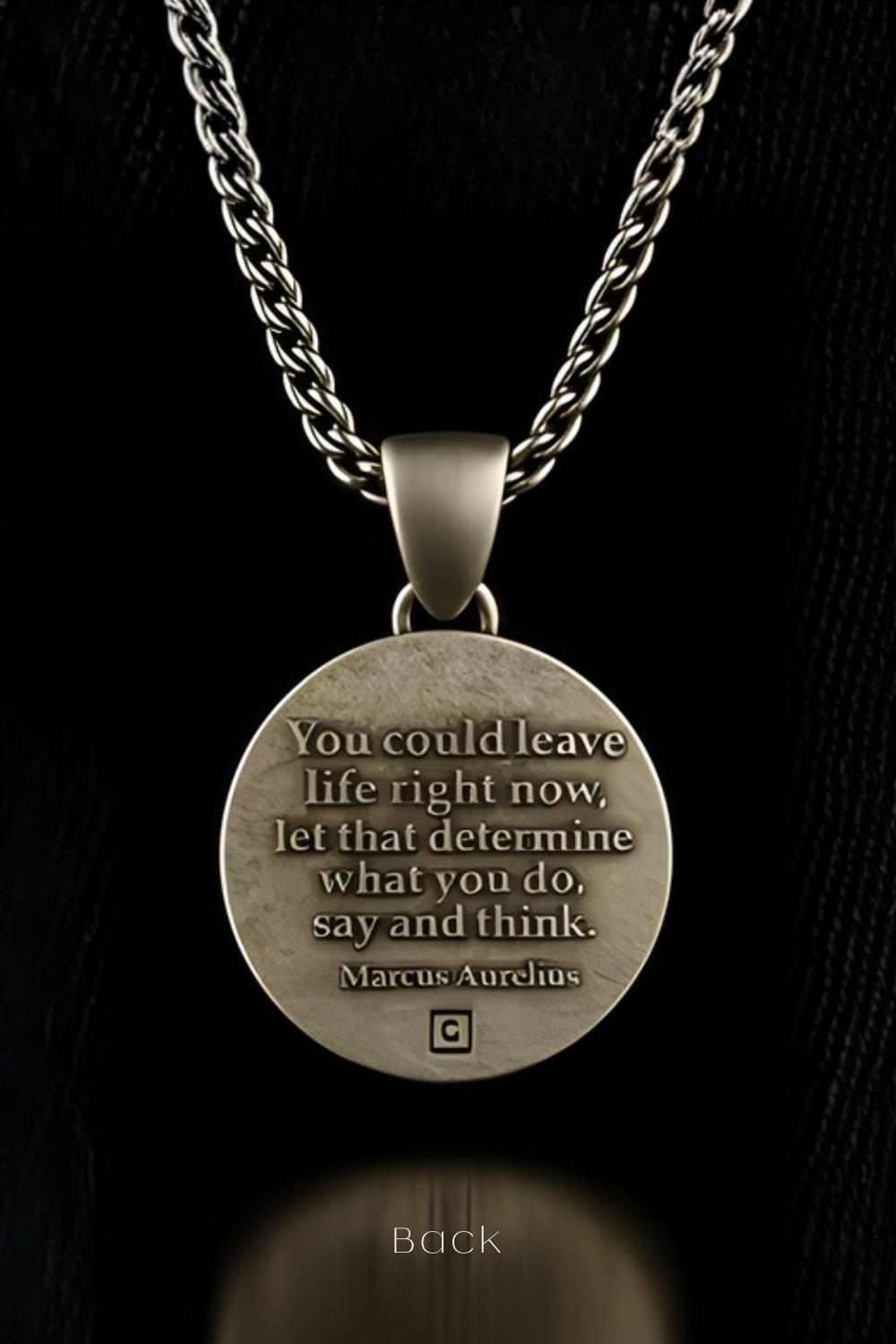 A silver-colored pendant necklace with a round medallion featuring a quote by Marcus Aurelius.