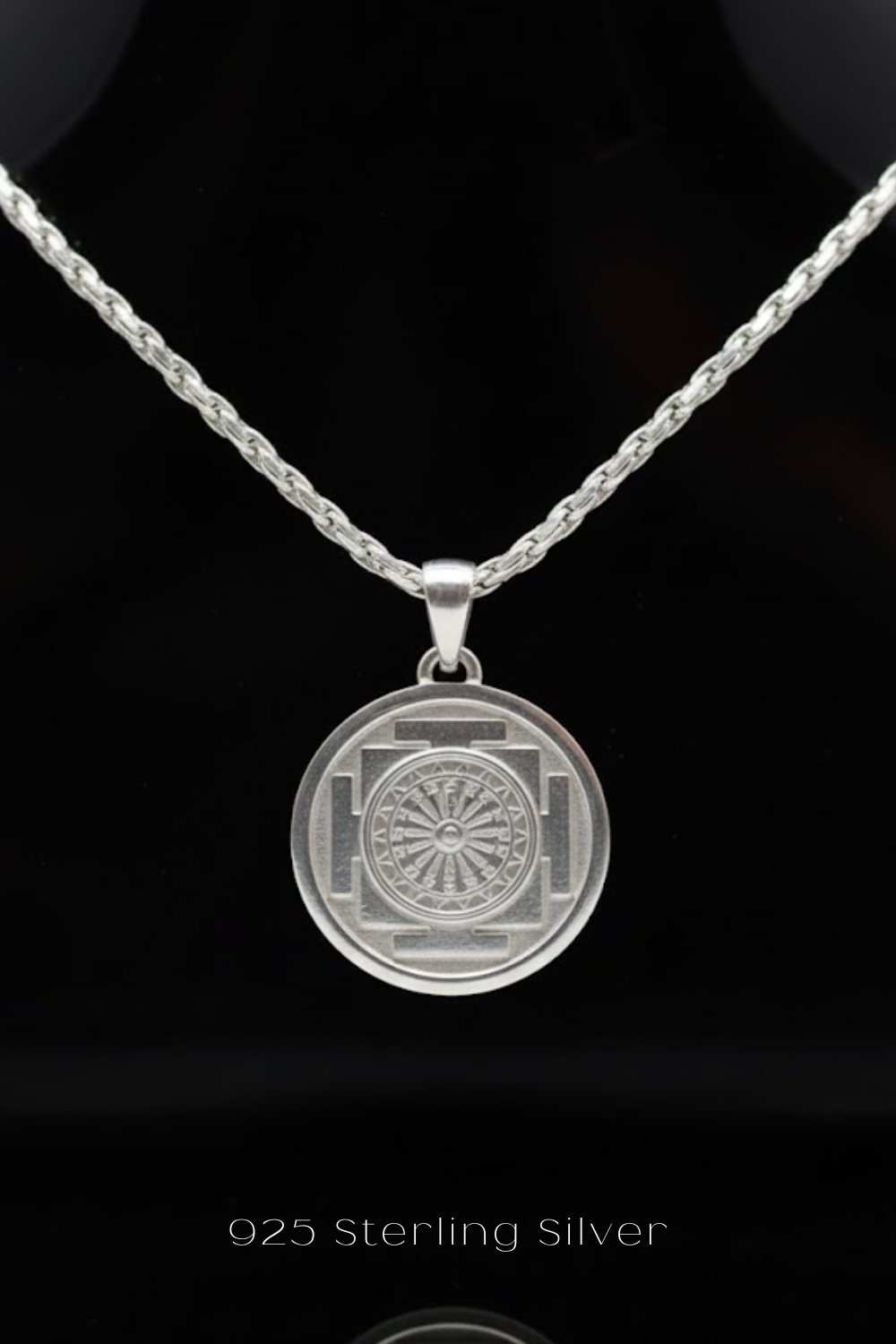 A silver necklace with a circular pendant featuring a medallion-like design.