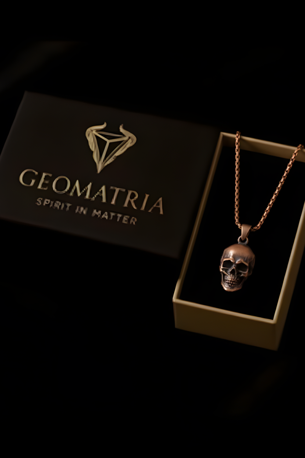 a necklace with a skull pendant, displayed in a box with the text "Geomatria Spirit in Matter" printed on it.
