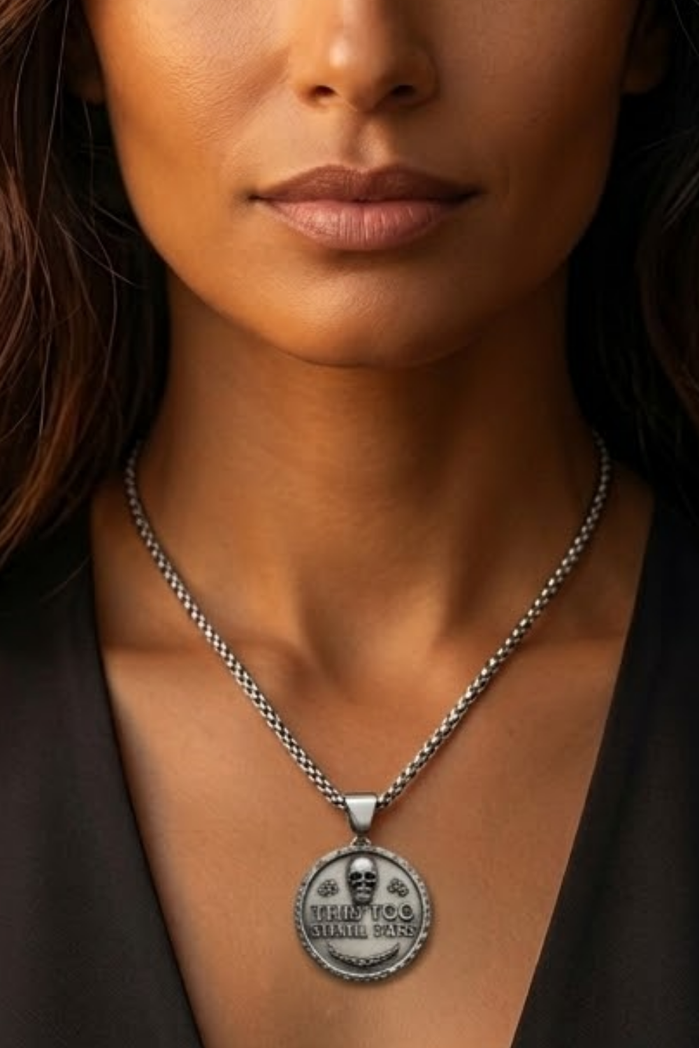 A close-up of a woman's neck and chest area, with a silver necklace featuring a pendant with a skull design.