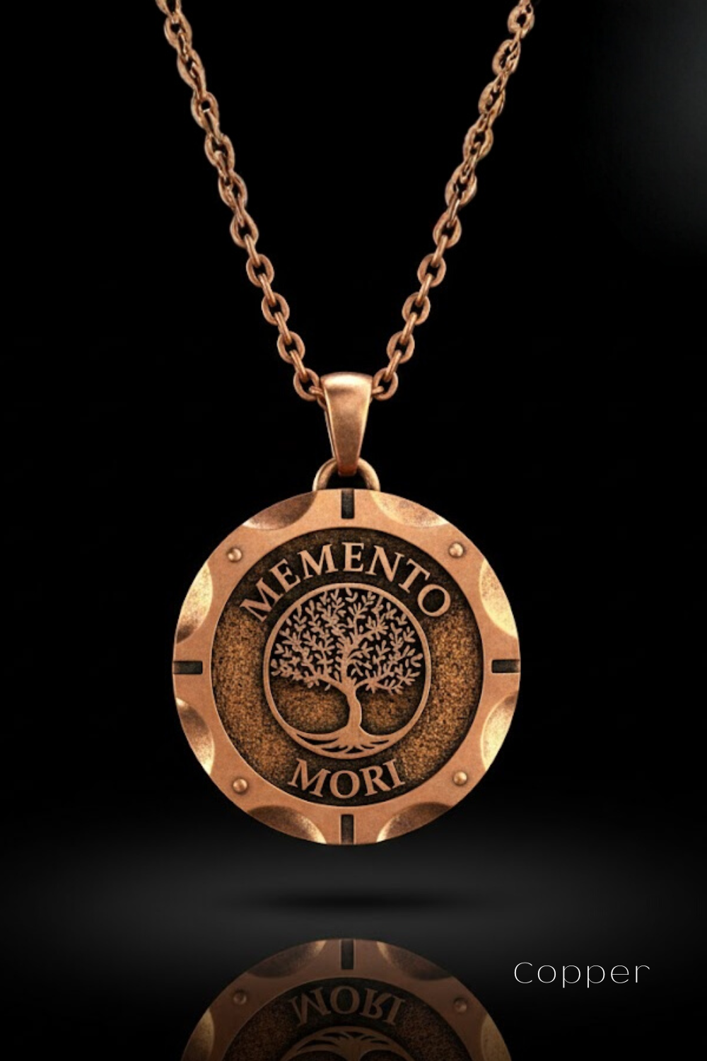 A copper-colored pendant necklace with a circular medallion featuring the text "MEMENTO MORI" and a tree design.