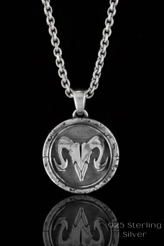 A silver-toned pendant necklace with a circular medallion featuring a ram's head design.