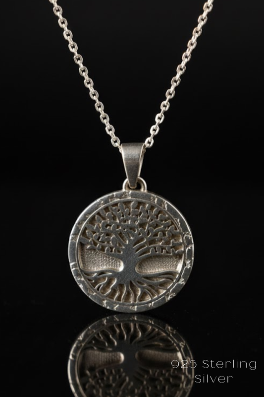 A silver tree pendant necklace with a reflective surface below it.